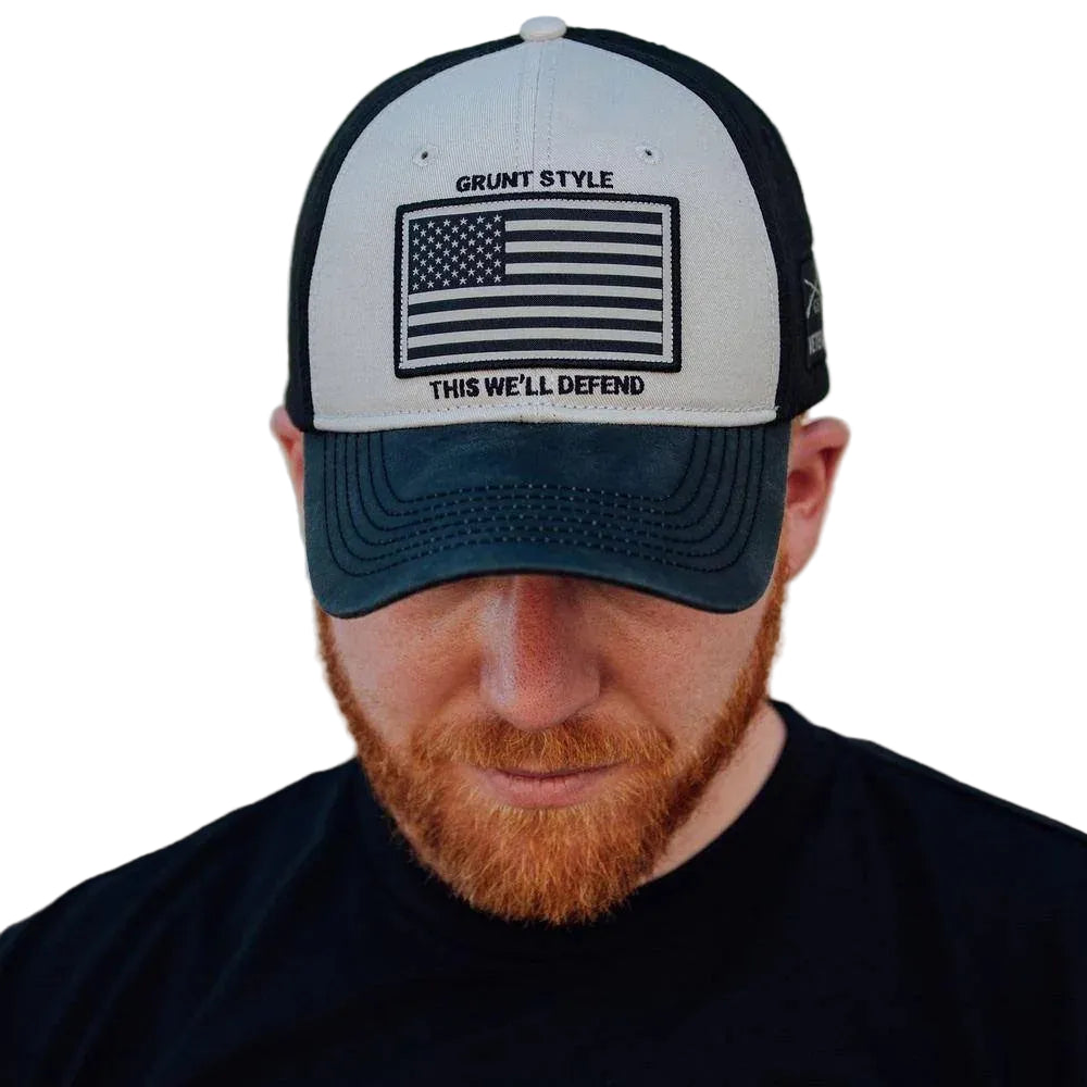 Man wearing a cap with an American flag design and text, against a neutral background
